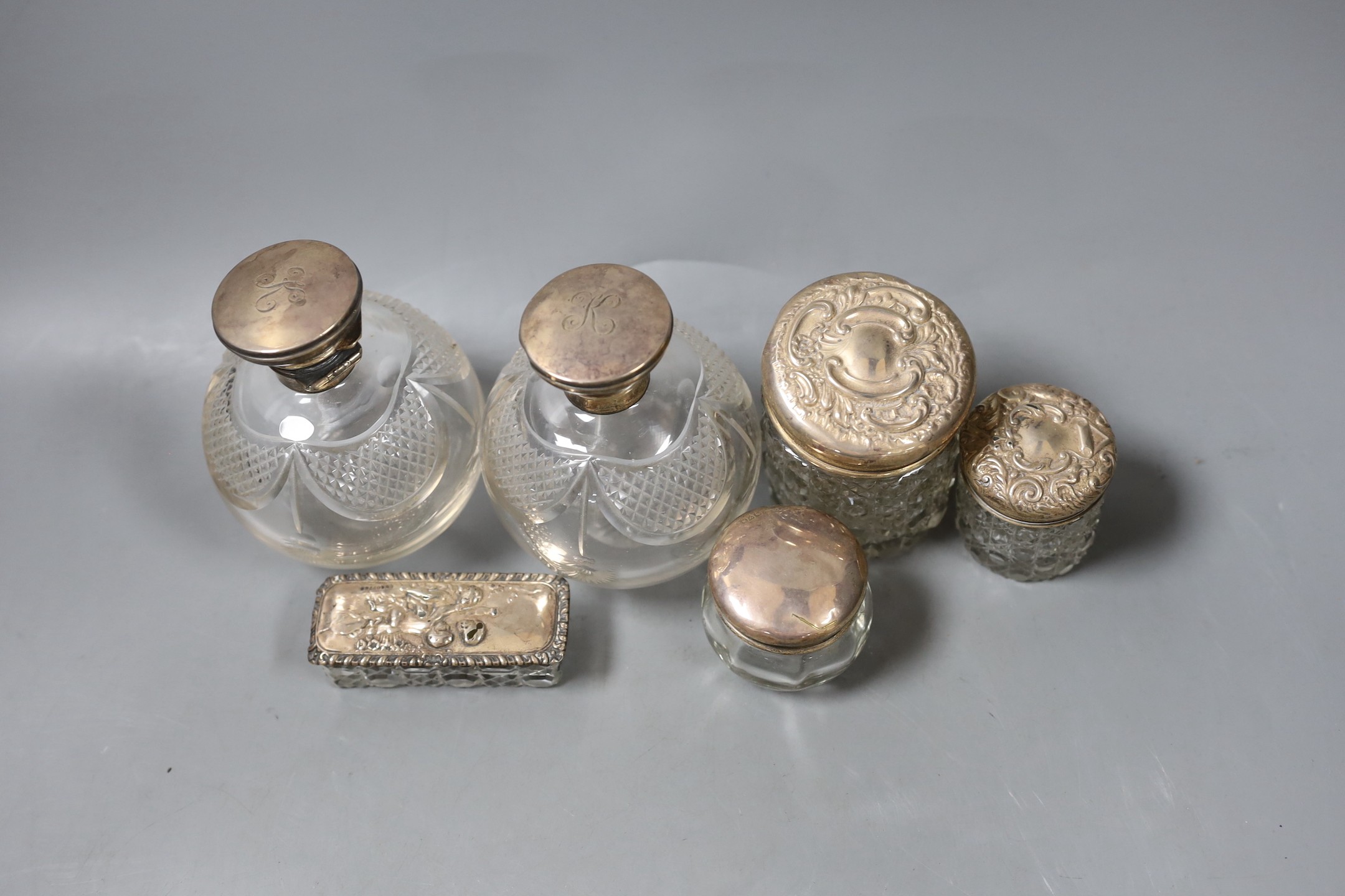 A pair of George V silver topped cut glass scent bottles, 11cm and four silver topped toilet jars.